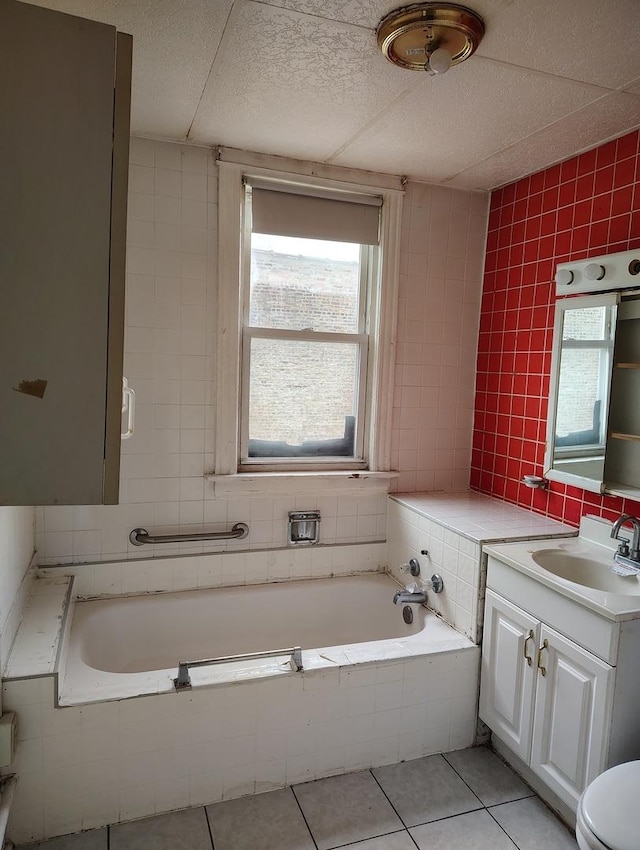 bathroom with tile patterned floors, tiled bath, plenty of natural light, and vanity