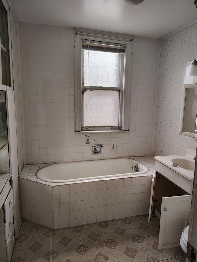 bathroom with tile patterned floors, tiled tub, and vanity