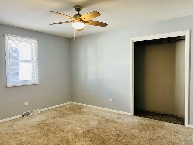 unfurnished bedroom with a closet, light colored carpet, and ceiling fan