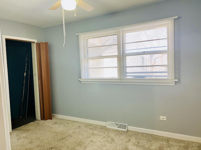 empty room with ceiling fan and light colored carpet