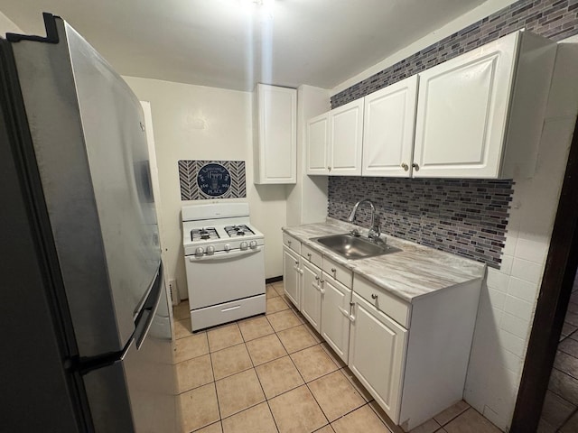 kitchen featuring white cabinetry, white gas range, stainless steel fridge, and sink