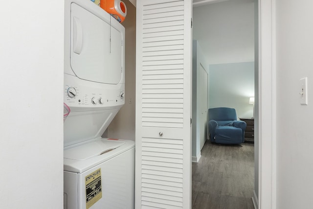 laundry room featuring wood-type flooring and stacked washer / dryer