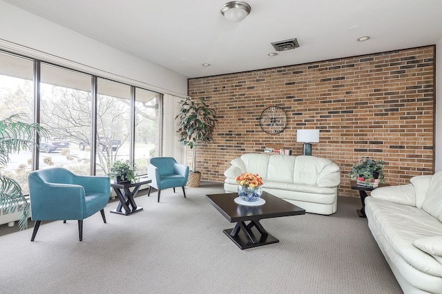 carpeted living room with brick wall