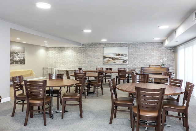 dining room with carpet floors and brick wall