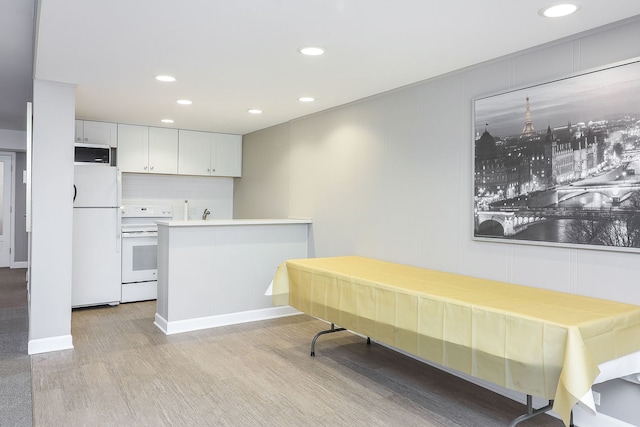 kitchen with white cabinets, white appliances, kitchen peninsula, and light hardwood / wood-style floors