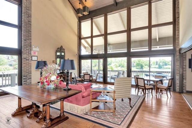 living room featuring a towering ceiling, a healthy amount of sunlight, and light wood-type flooring