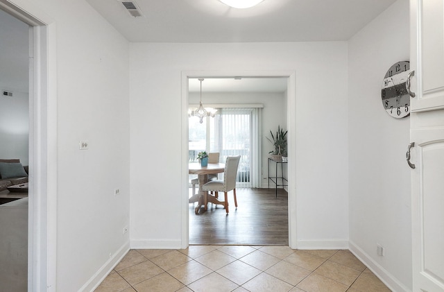 hall featuring a notable chandelier and light tile patterned flooring