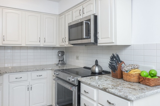 kitchen with white cabinets, light stone counters, stainless steel appliances, and tasteful backsplash