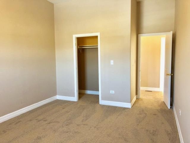 unfurnished bedroom with light carpet and a closet