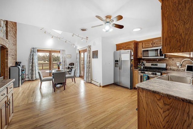 kitchen featuring appliances with stainless steel finishes, backsplash, ceiling fan, sink, and a baseboard radiator