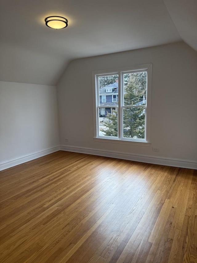 additional living space with light hardwood / wood-style floors and vaulted ceiling