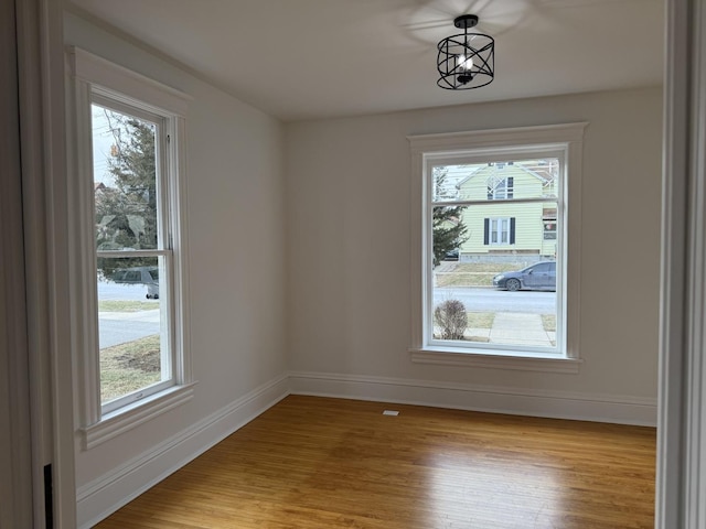 unfurnished dining area featuring plenty of natural light, a notable chandelier, and light hardwood / wood-style flooring