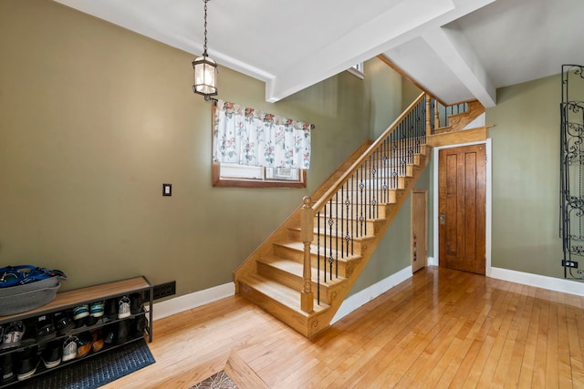 staircase with beamed ceiling and hardwood / wood-style flooring