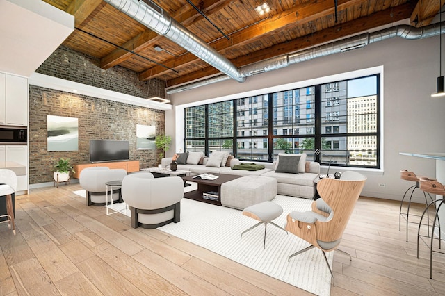 living room featuring beamed ceiling, brick wall, light wood-type flooring, and wood ceiling