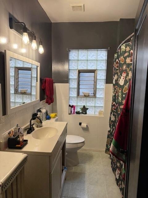 bathroom with vanity, toilet, tile walls, and plenty of natural light