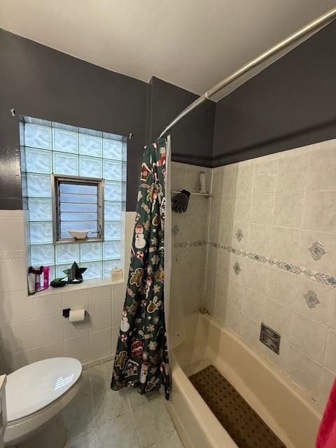 bathroom featuring tile patterned floors, toilet, and shower / bathtub combination with curtain