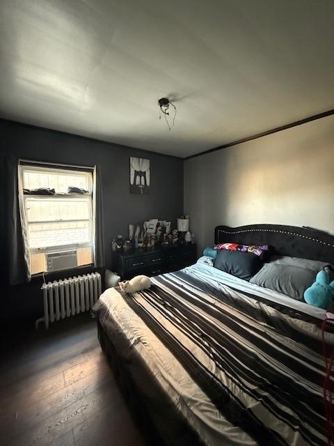 bedroom with dark wood-type flooring, cooling unit, and radiator