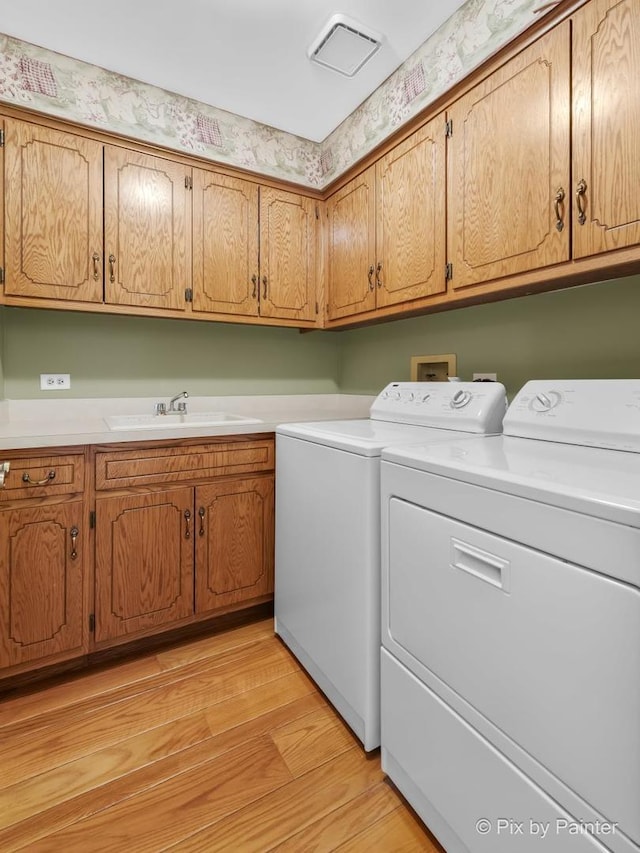 washroom with washer and clothes dryer, cabinets, light wood-type flooring, and sink