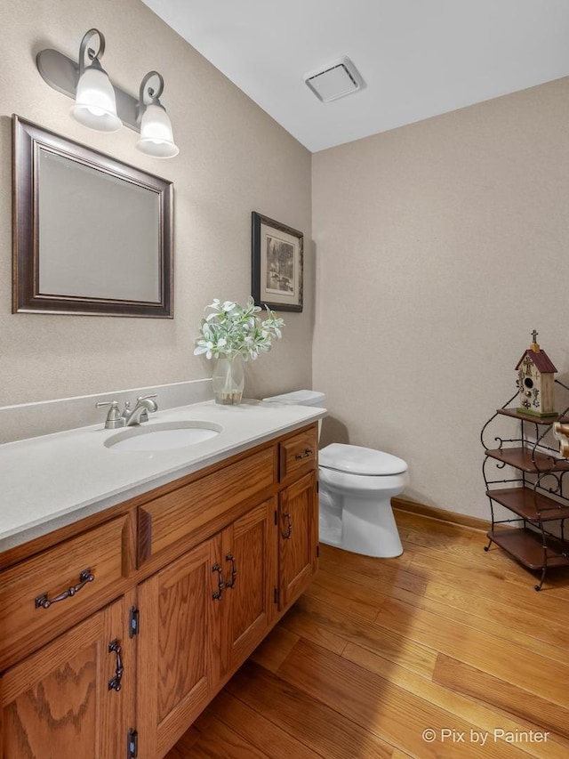 bathroom with hardwood / wood-style floors, vanity, and toilet