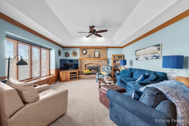 living room featuring carpet flooring, ceiling fan, a raised ceiling, wooden walls, and a fireplace