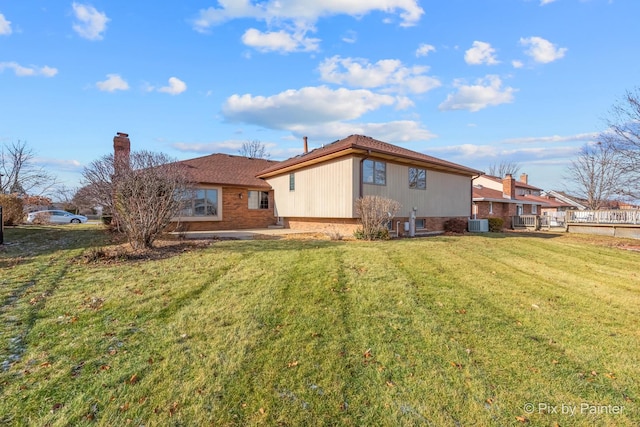 rear view of property featuring a yard and cooling unit