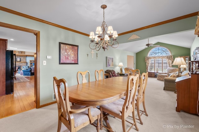 carpeted dining area featuring ceiling fan with notable chandelier, vaulted ceiling, and ornamental molding