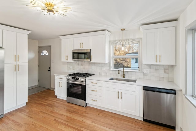 kitchen with white cabinets, backsplash, sink, and appliances with stainless steel finishes