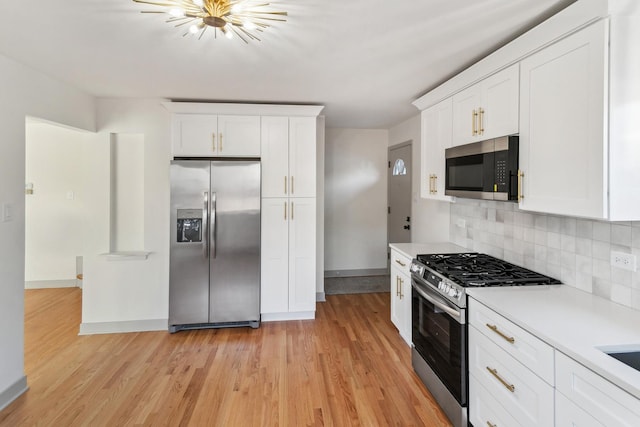 kitchen with tasteful backsplash, white cabinets, light wood-type flooring, and appliances with stainless steel finishes