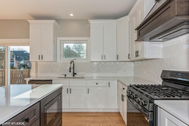 kitchen with premium range hood, white cabinets, sink, and black appliances