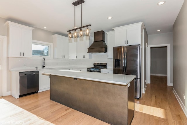 kitchen featuring sink, appliances with stainless steel finishes, a kitchen island, decorative light fixtures, and custom exhaust hood