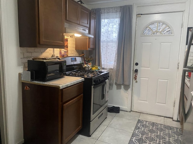 kitchen featuring tasteful backsplash, dark brown cabinets, light tile patterned floors, and stainless steel range with gas stovetop