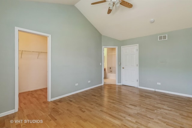 unfurnished bedroom with light wood-type flooring, a spacious closet, ceiling fan, and a closet