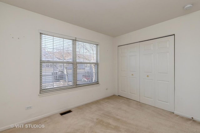 unfurnished bedroom with light colored carpet and a closet