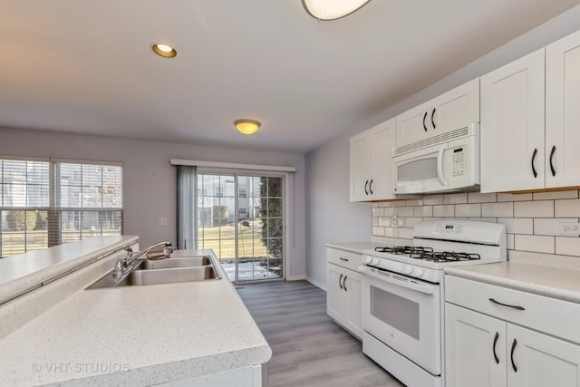 kitchen featuring sink, white appliances, decorative backsplash, and white cabinetry