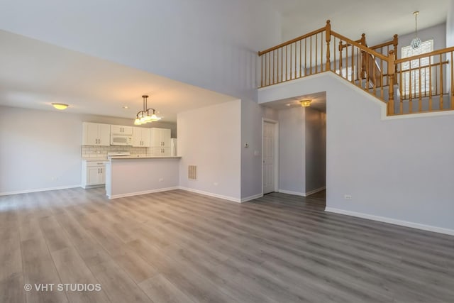 unfurnished living room featuring light hardwood / wood-style floors and a high ceiling