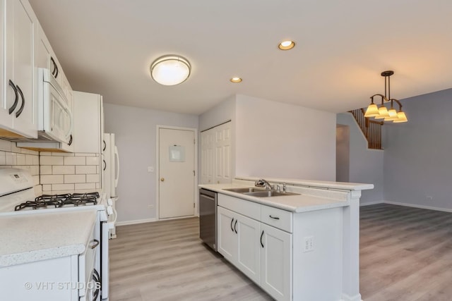 kitchen featuring sink, hanging light fixtures, an island with sink, white appliances, and white cabinets