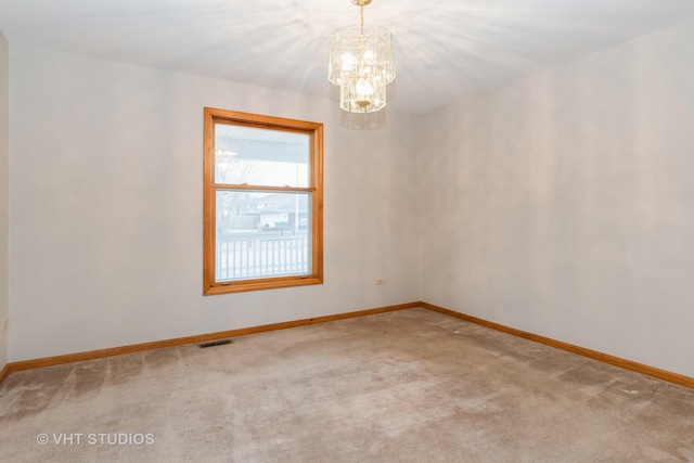 carpeted spare room featuring a chandelier