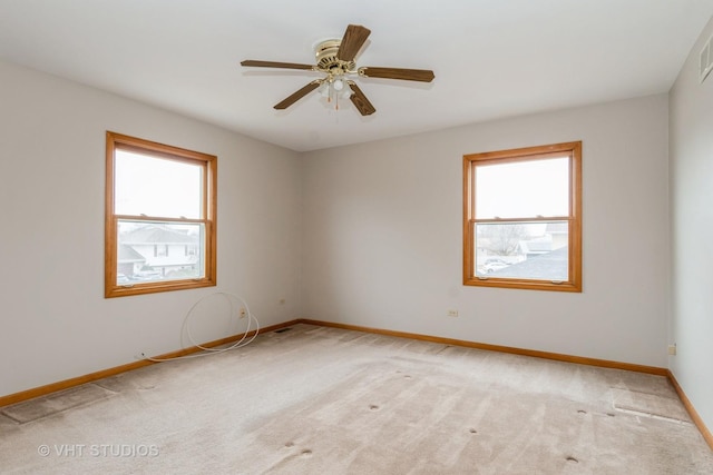 carpeted spare room featuring a wealth of natural light and ceiling fan