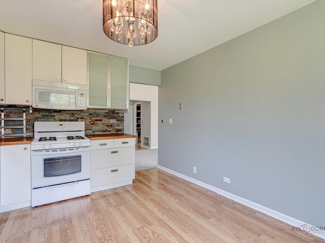 kitchen with backsplash, white cabinets, white appliances, and a notable chandelier