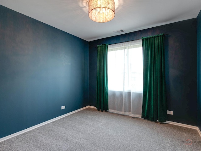 unfurnished room with carpet flooring and a chandelier