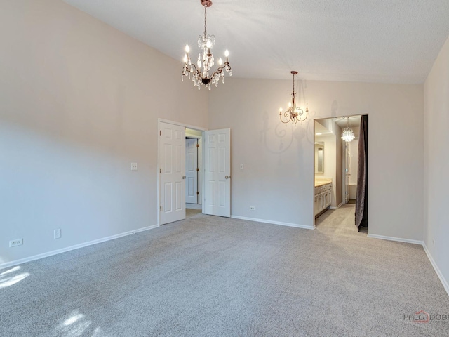 carpeted empty room with a chandelier, a textured ceiling, and vaulted ceiling