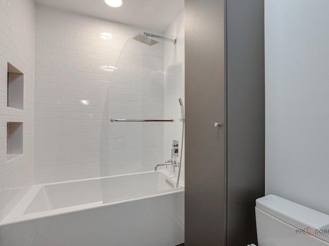 bathroom with tiled shower / bath combo and toilet