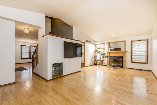 unfurnished living room with vaulted ceiling, light hardwood / wood-style floors, and a chandelier