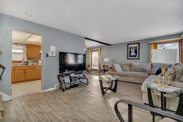 living room with a wealth of natural light, light hardwood / wood-style flooring, ceiling fan, and sink