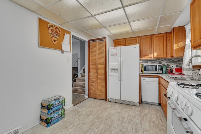 kitchen featuring backsplash, a paneled ceiling, white appliances, sink, and light hardwood / wood-style flooring