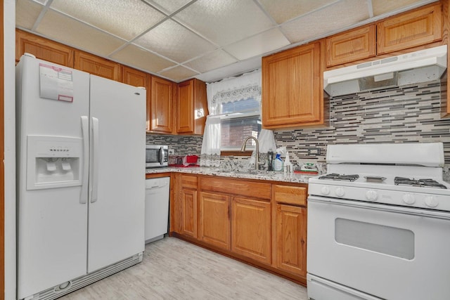 kitchen with a paneled ceiling, backsplash, white appliances, and sink