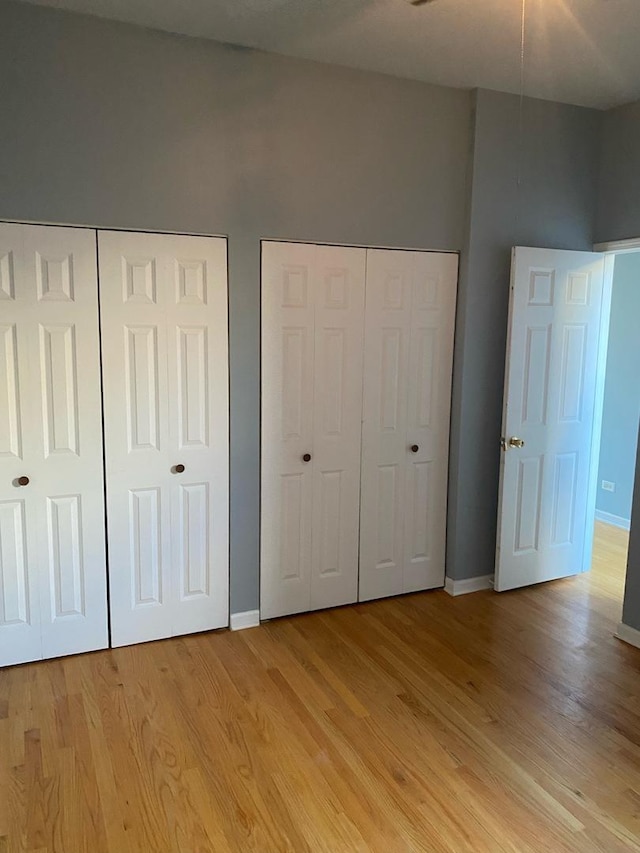 unfurnished bedroom featuring light hardwood / wood-style flooring and multiple closets