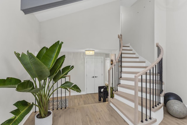 staircase with vaulted ceiling with beams and hardwood / wood-style flooring