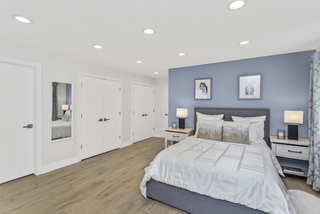 bedroom with multiple closets and light hardwood / wood-style flooring