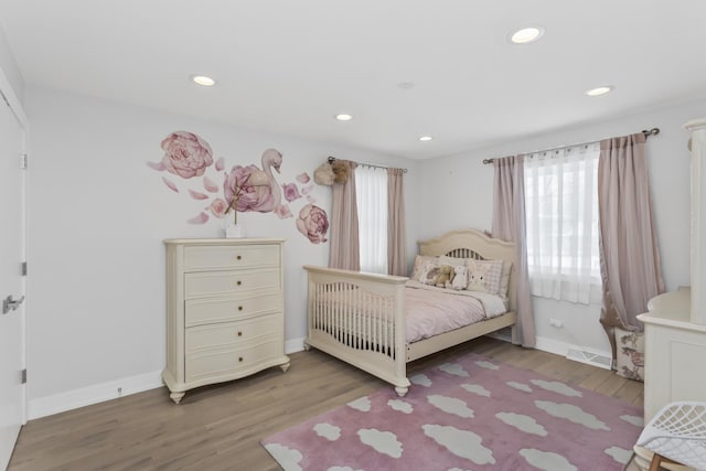 bedroom with wood-type flooring and multiple windows